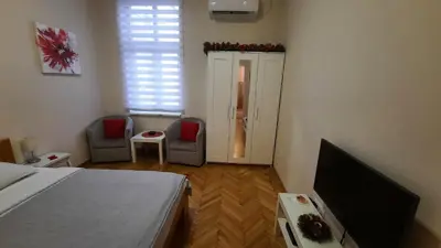 a bedroom with a bed and two chairs and a television at Belgrade 1911 apartment in Belgrade