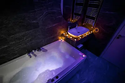 a bathroom with a tub and a sink with lights at Sinergija in Belgrade