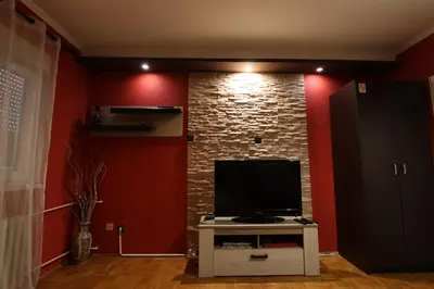 a living room with a tv and a brick wall at Two Rivers Apartment in Belgrade