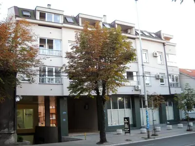 a white building with a tree in front of it at Residence Amelie in Belgrade