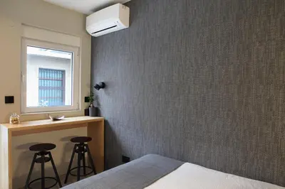 a bedroom with a bed and a window and stools at Temple Apartments Belgrade in Belgrade