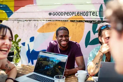 a group of people sitting at a table with a laptop at Good People Design Hostel in Belgrade
