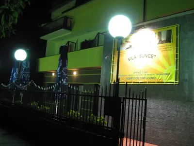 a building with two street lights next to a fence at Hotel Vila Sunce in Stara Pazova