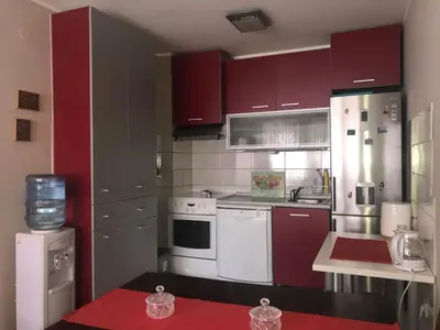 a kitchen with red cabinets and white appliances at Apartman AS in Belgrade