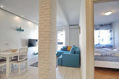 a living room with a blue couch and a bedroom at Bianca in Belgrade