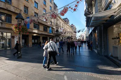 a group of people walking down a street with buildings at Jolie in Belgrade