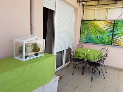 a balcony with a green table and chairs and a fish tank at Jolie in Belgrade