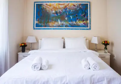 a bedroom with a white bed with a painting on the wall at Crown apartment with garden view in Belgrade