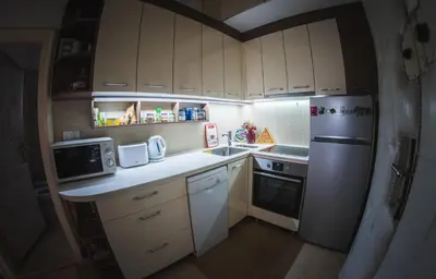 a small kitchen with white cabinets and a refrigerator at Crown apartment with garden view in Belgrade