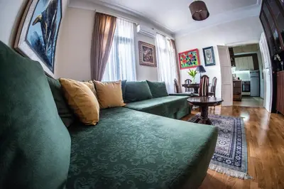 a living room with a green couch and a table at Crown apartment with garden view in Belgrade