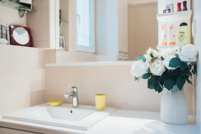 a bathroom with a sink and a vase with white flowers at Crown apartment with garden view in Belgrade