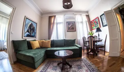 a living room with a green couch and a table at Crown apartment with garden view in Belgrade