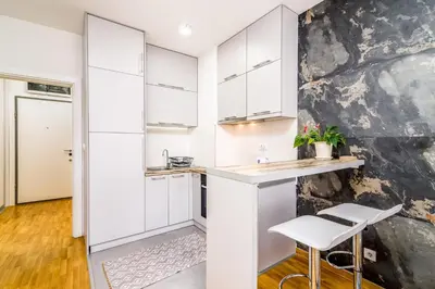 a kitchen with white cabinets and a counter and stools at Loko Savada in Belgrade