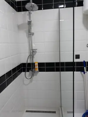 a shower in a bathroom with black and white tiles at Sweet Yellow Apartment in Belgrade