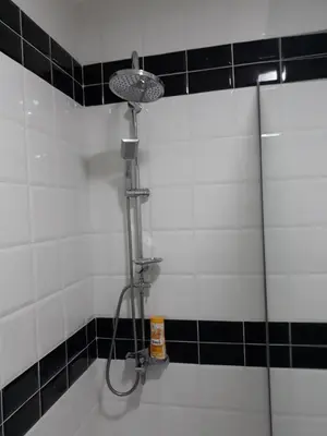 a shower in a bathroom with black and white tiles at Sweet Yellow Apartment in Belgrade