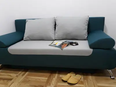 a blue couch with a magazine and pair of shoes at Sweet Yellow Apartment in Belgrade