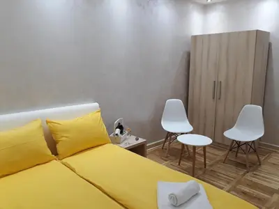 a bedroom with a yellow bed and two white chairs at Sweet Yellow Apartment in Belgrade
