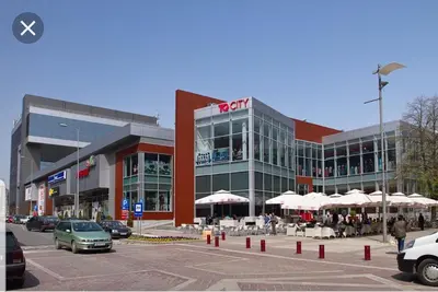 a building with a car parked in a parking lot at Apartman SUN in Inđija