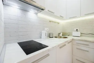 a white kitchen with white cabinets and a sink at Apartment Hana Lux-Cozy Studio Near Danube, Quite & Bright in Belgrade