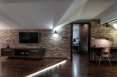 a living room with a tv and a brick wall at ONE Apartment in Belgrade