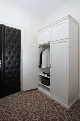 a closet with white cabinets and a black door at Booking Rooms in Belgrade