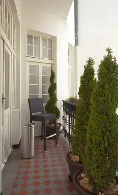 a porch with a bench and potted trees on a house at Booking Rooms in Belgrade
