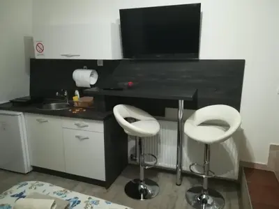 a kitchen with two white stools and a black counter at Prenoćište Day Holiday in Smederevo