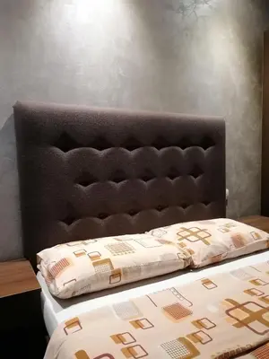 a bed with a black headboard and pillows on it at Prenoćište Day Holiday in Smederevo