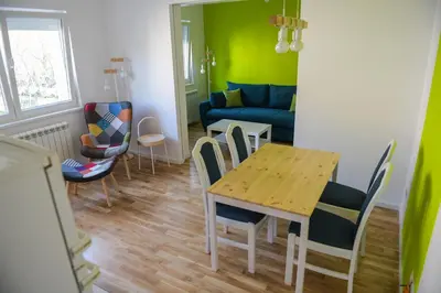 a living room with a table and chairs and a couch at Puzzle Apartment in Dedinje