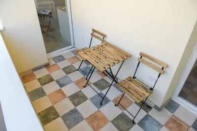 two wooden chairs sitting on a tiled floor at Puzzle Apartment in Dedinje