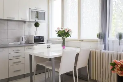 a kitchen with a table with white chairs and a vase of flowers at GRACE in Tošin Bunar