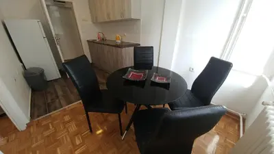 a black table and chairs in a kitchen with a refrigerator at Apartment Delta Sava New Belgrade in Belgrade