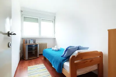a bedroom with a bed with blue sheets and a window at Belgrade Sweet Home Apartment in Belgrade