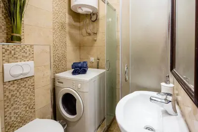 a bathroom with a toilet a sink and a washing machine at The Duke Apartment in Belgrade