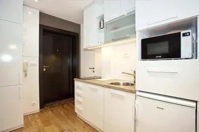 a white kitchen with a sink and a microwave at HostGost Selected Suites - Skadarlija Square in Belgrade