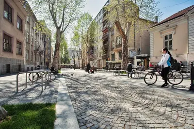 a woman walking her bike down a cobblestone street at HostGost Selected Suites - Skadarlija Square in Belgrade