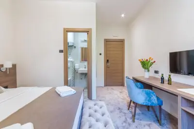 a bedroom with a desk and a bed with a blue chair at M House Belgrade Residence in Belgrade