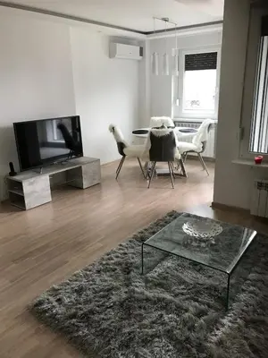 a living room with a television and a table and chairs at Apartman Oslo in Belgrade