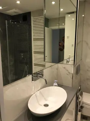 a man taking a picture of a bathroom with a sink at Apartman Oslo in Belgrade