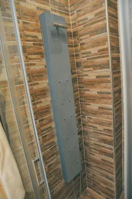 a shower in a room with wooden wall at Apartman Las Vegas in Belgrade