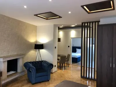 a living room with a blue chair and a bedroom at Aria Royal apartment in Belgrade