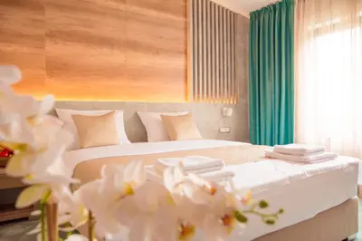 a bedroom with a bed with white sheets and flowers at Hotel Nota in Belgrade