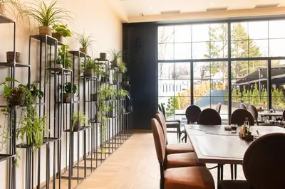 a restaurant with tables and chairs and plants on the wall at Hotel Nota in Belgrade