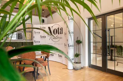 a room with a table and a wall with a vola sign at Hotel Nota in Belgrade