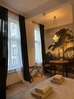 a bedroom with a bed and a table and windows at Oaza 26 in Belgrade