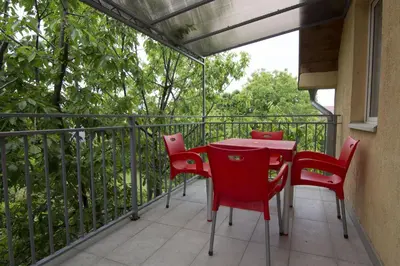a patio with red chairs and a table on a balcony at Dolce Casa in Belgrade