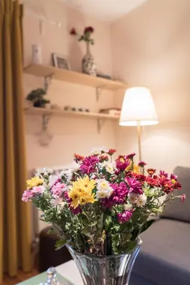 a vase of flowers on a table with a lamp at Skadarlija City Break in Belgrade