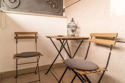two stools and a table with a bird cage on a wall at Skadarlija City Break in Belgrade