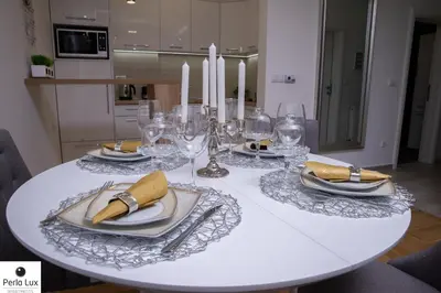 a white table with plates and glasses and candles at Perla Lux Apartments in Arandjelovac