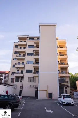 a white car parked in a parking lot in front of a building at Perla Lux Apartments in Arandjelovac
